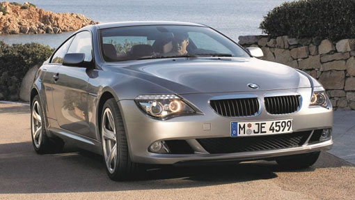 Image of silver BMW parked on road near the sea, taken from the front of the car