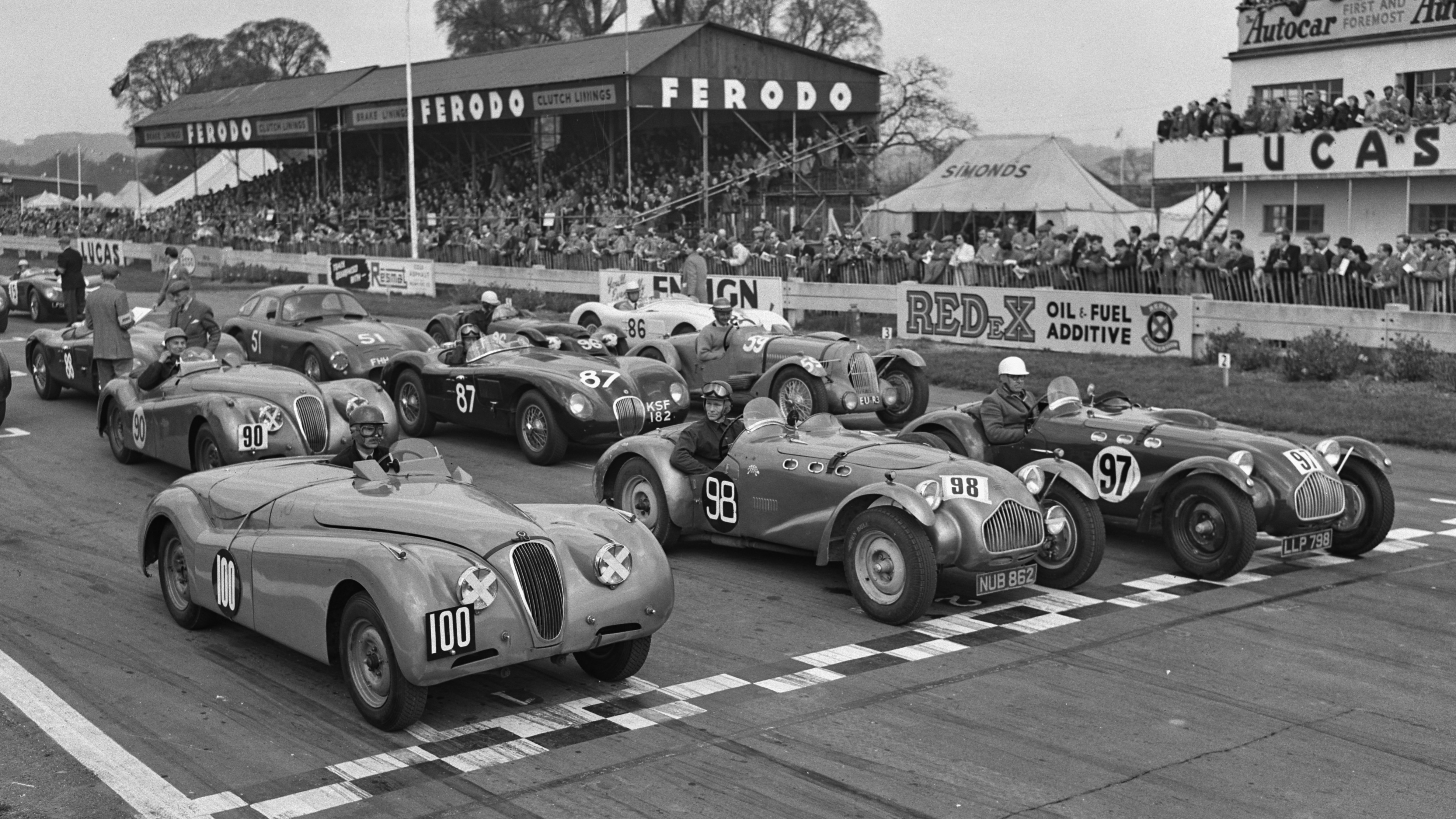 Dick Protheroe lines up for the start of the first Easter Handicap race at Goodwood in April 1954 in the #100 Jaguar XK120.