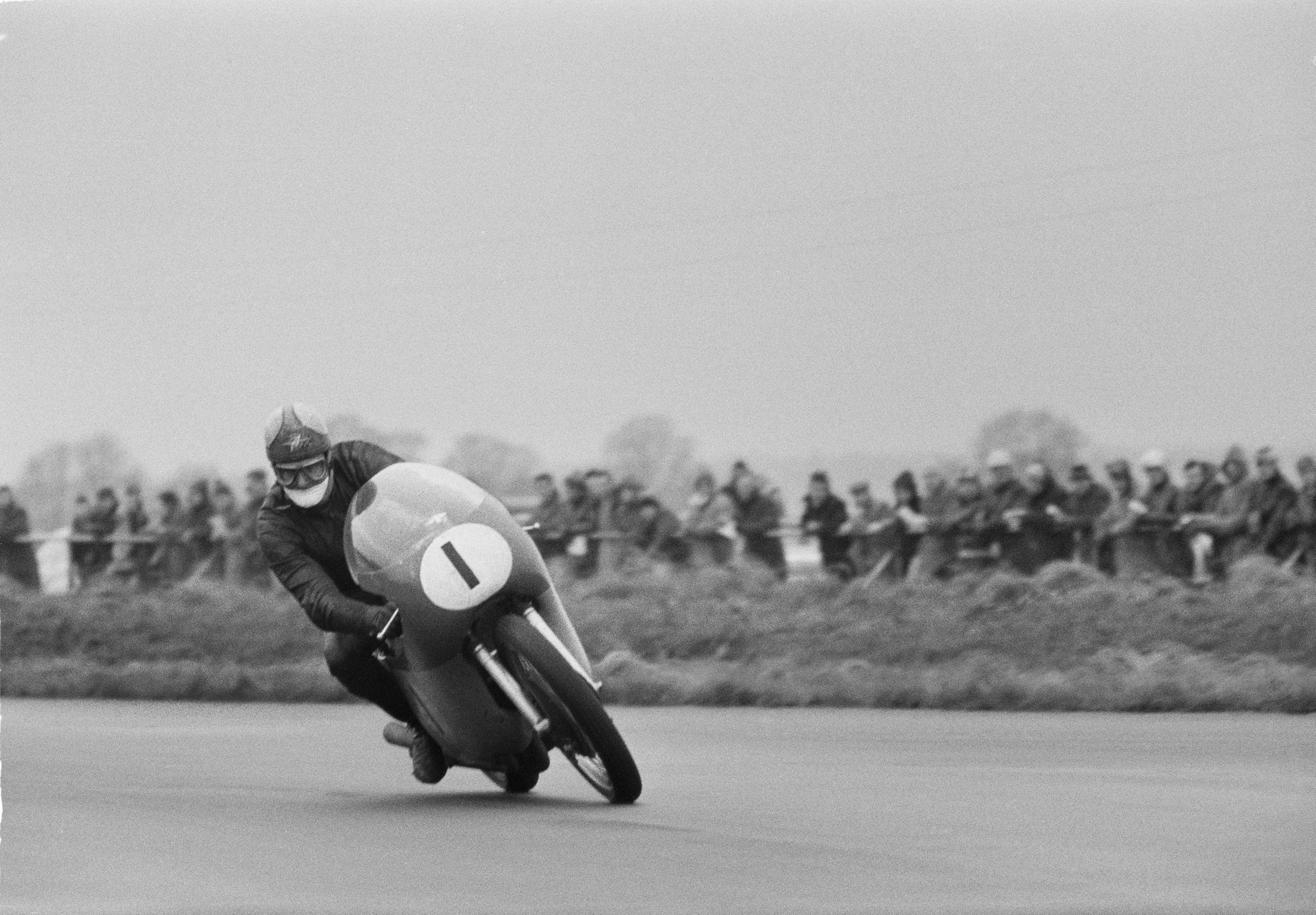 Mike Hailwood atop his #1 MV Agusta on his way to victory in the 1964 500cc Hutchinson 100 race at Silverstone.