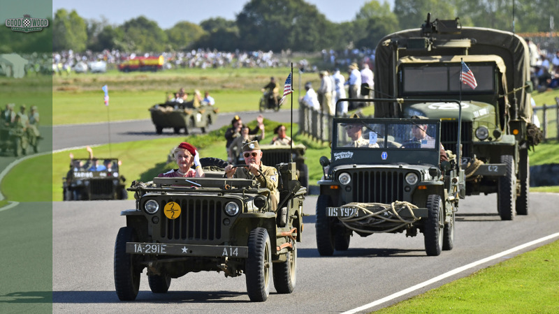 A convoy of restored Second World War vehicles parades around the Goodwood Motor Circuit.