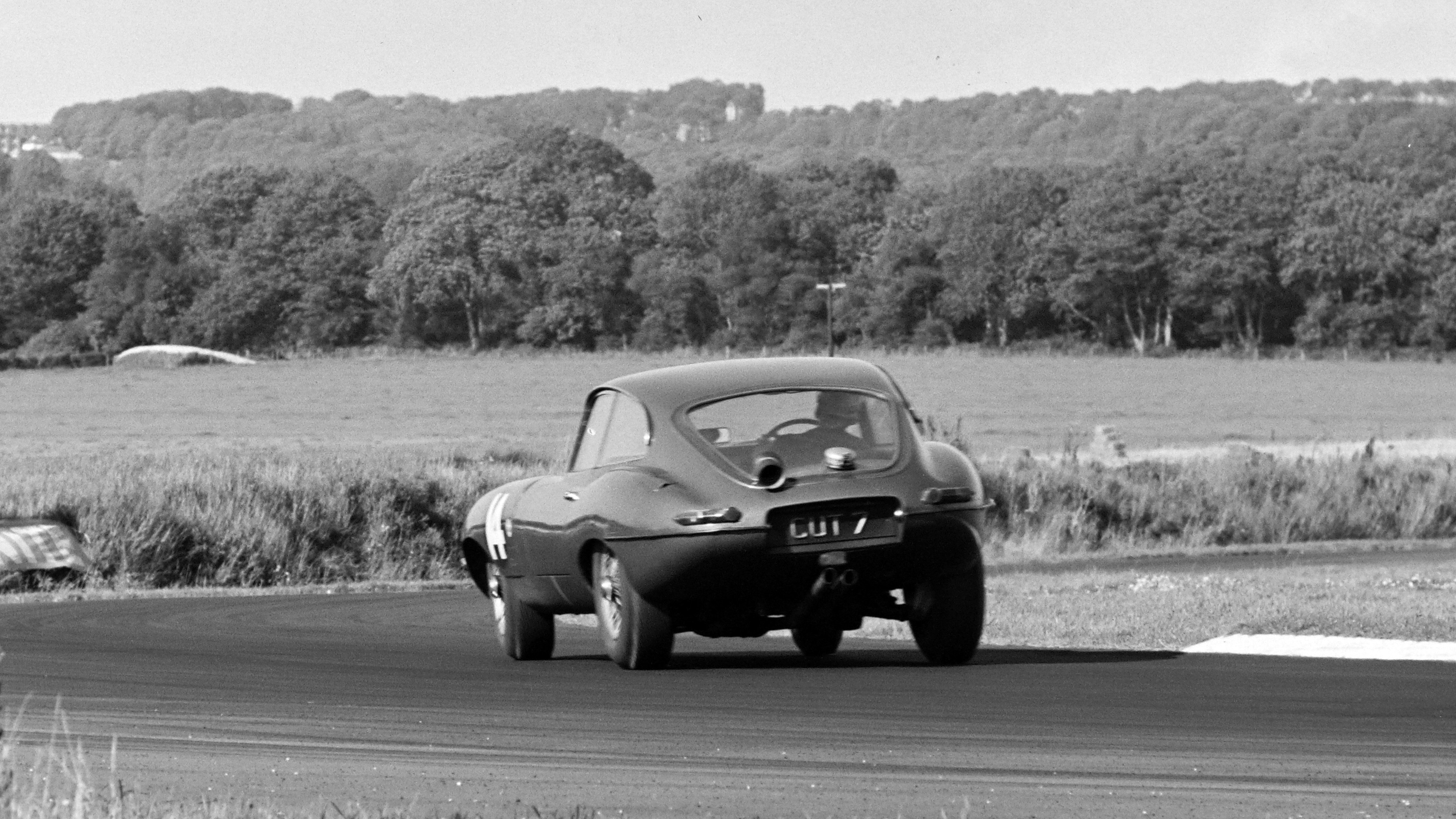 Dick Protheroe races his CUT 7-plated Jaguar E-type during the RAC Tourist Trophy at the Goodwood Motor Circuit, August 1962.