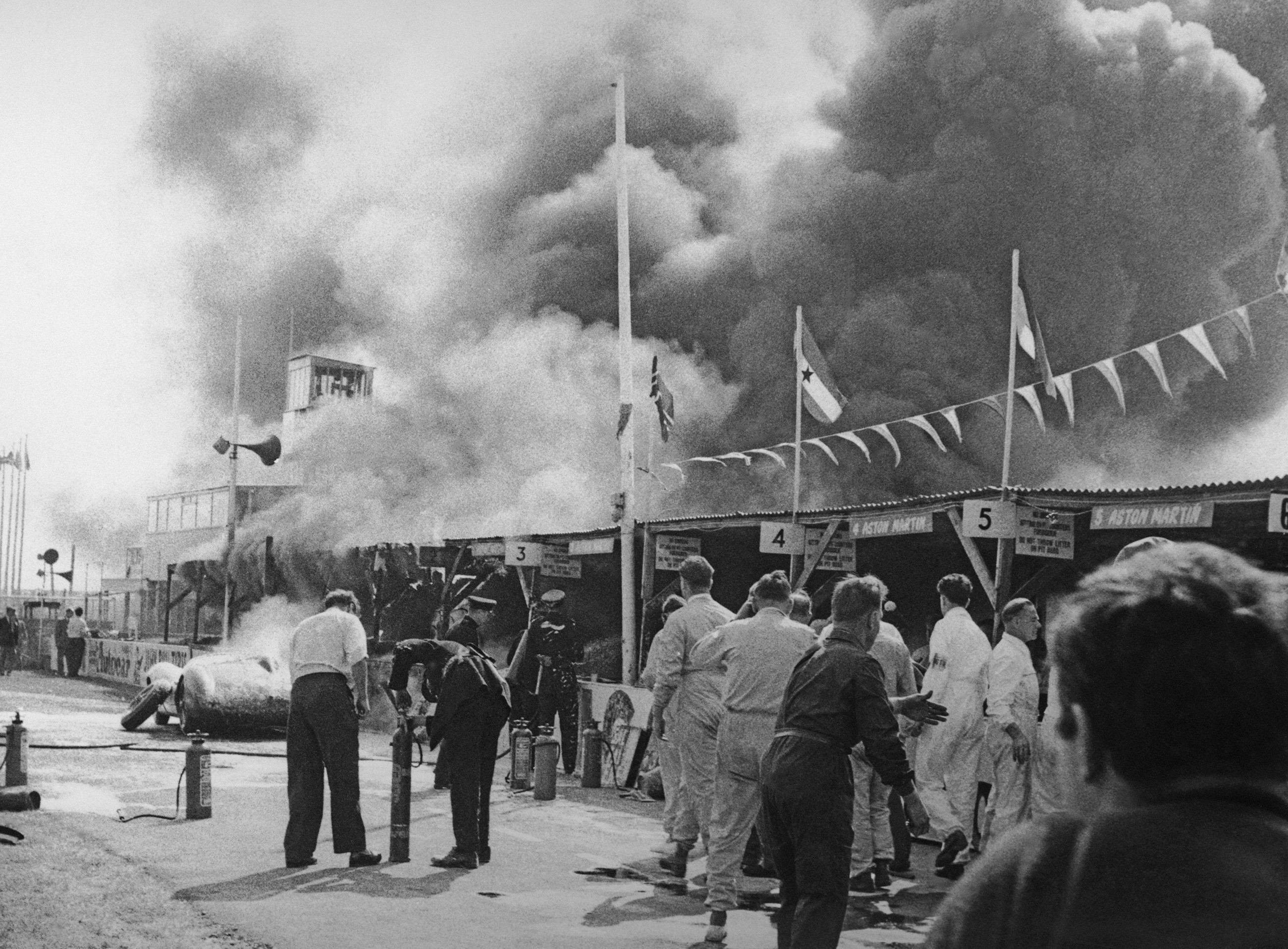 Roy Salvadori's Aston Martin racing car burning in the pits during the RAC Tourist Trophy race at Goodwood on 8th September 1959. The car caught fire during a new high-speed refuelling process, injuring Salvadori.