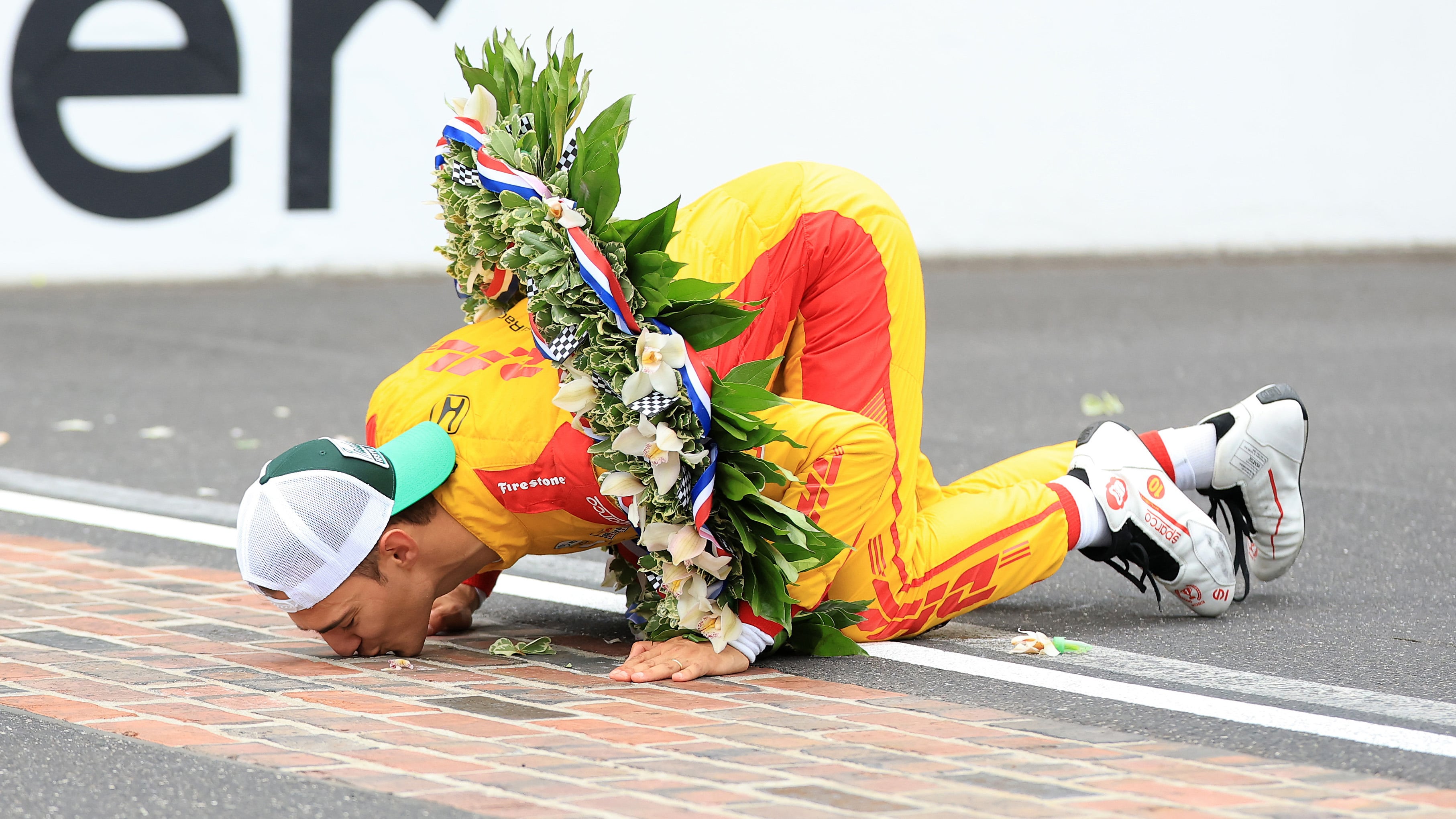 Alex Palou kisses the bricks after taking his first win at Indianapolis in 2025.