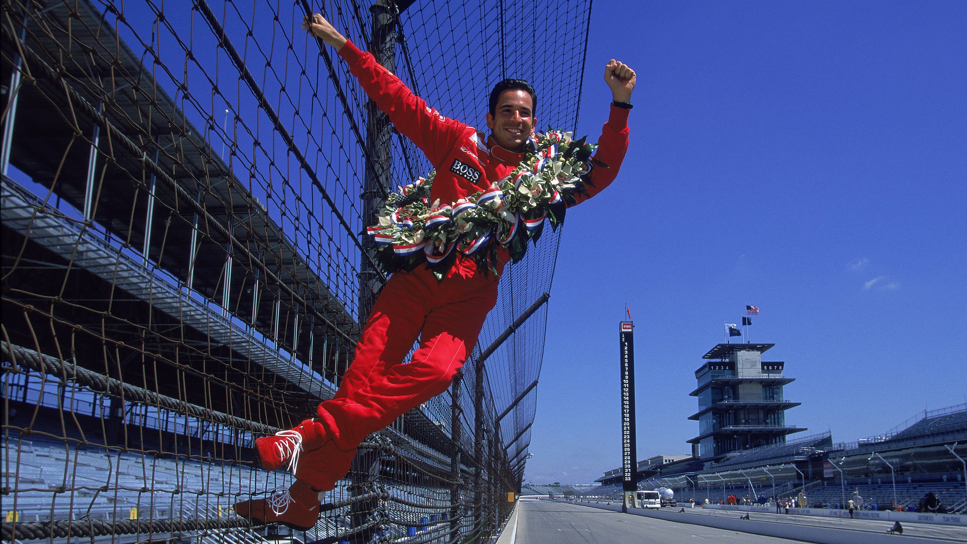 Castroneves celebrates winning the Indianapolis 500 for the first time with his iconic climbing of the fence, May 2001.