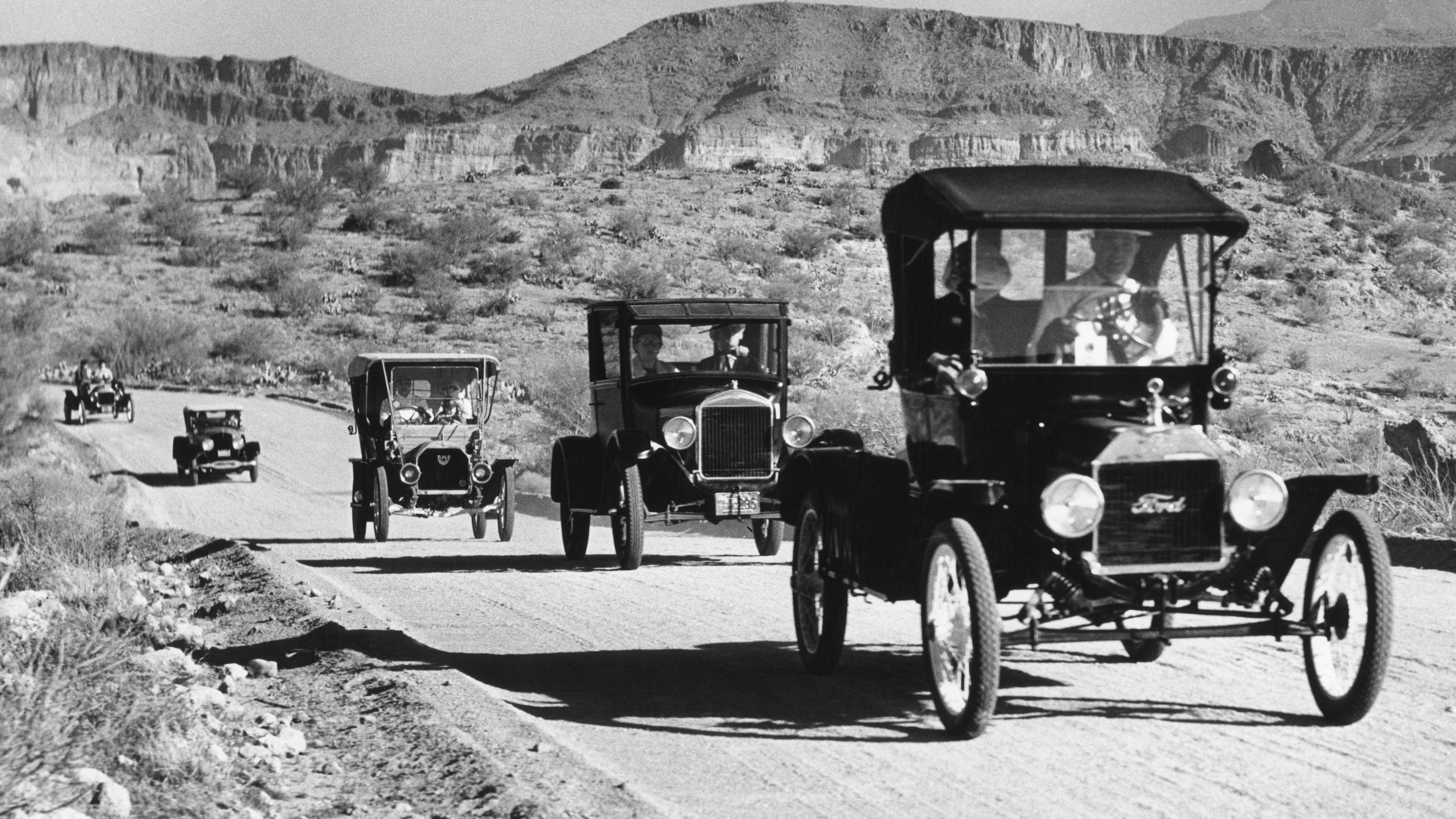 Ford Model Ts and Model As from the 1920s travel in a convoy in the Southwest of America.