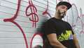 New York DJ, Roger Sanchez, is photographed against red graffiti.